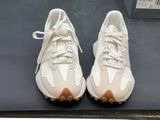pair of white sneakers with brown soles on display in a store