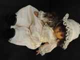 a doll that is wearing a white dress and a hat
