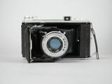 an old black camera with a blue lens sitting on a white surface