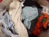 a basket full of clothes that is sitting on a bed