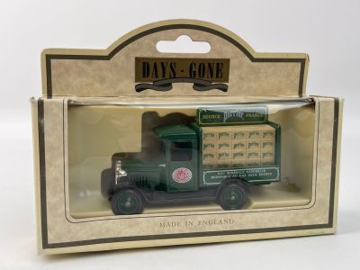 un petit camion vert dans une boîte, posé sur une surface blanche