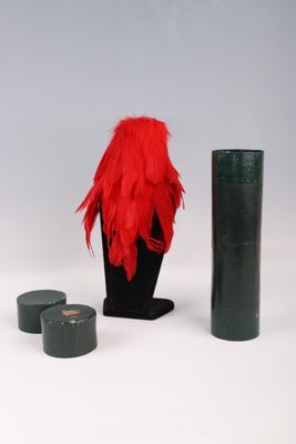 a red feathered hat and a green vase on a white table