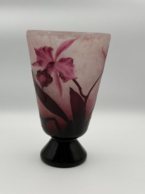 a vase with a pink flower on it on a black stand