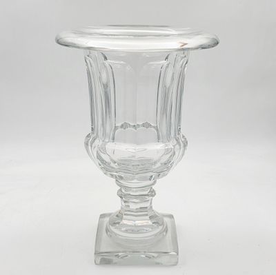un vase en verre transparent posé sur un socle, sur fond blanc