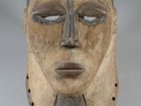 a close up of a wooden mask on a white surface