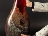 woman sitting on the floor holding a large red vase in her hands