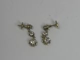 deux paires de boucles d'oreilles en diamant posées sur une surface blanche