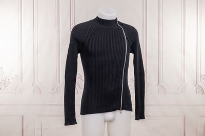 Le mannequin porte un pull noir et un pantalon blanc.