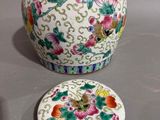 a vase with a lid sitting on a table next to a plate