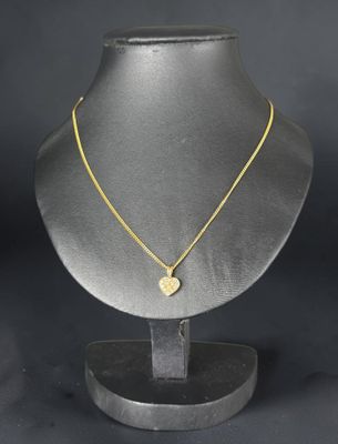 a gold necklace on a mannequin stand with a black background