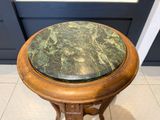 une table au plateau en marbre, avec un piètement en bois, posée sur un sol carrelé