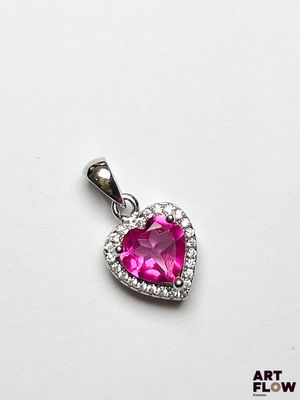 un gros plan d'un pendentif rose en forme de cœur posé sur une surface blanche