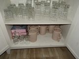 many cups and mugs sitting on a shelf in a cabinet