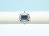 une bague en saphir bleu et diamants posée sur une serviette blanche