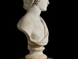 marble bust of a woman on a marble pedestal against a black background