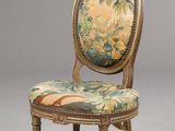 une chaise ancienne avec un dossier rembourré à motifs floraux et des pieds dorés