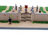 figurines of people standing in front of a gate on a cake