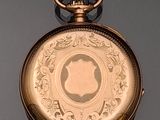 a gold pocket watch on a table with a black background