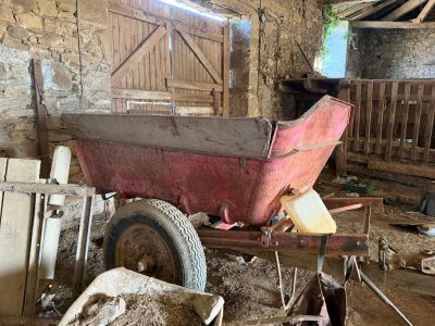 a red wagon sitting in the middle of a barn filled with sheep