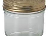 un bocal en verre vide avec un couvercle doré sur fond blanc