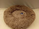 a brown dog bed on a bed with a white sheet