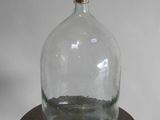une bouteille en verre posée sur un socle en bois, sur fond blanc