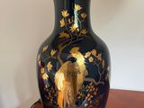 a black vase with a bird on it sitting on a table