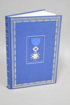 un vieux livre avec une couverture bleue sur laquelle est apposée une médaille