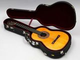 une guitare dans un étui, posée sur une surface blanche