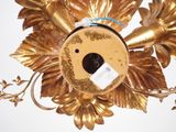 a gold flower with a tag on it hanging on a wall