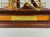 a miniature model of a steam engine on a wooden base