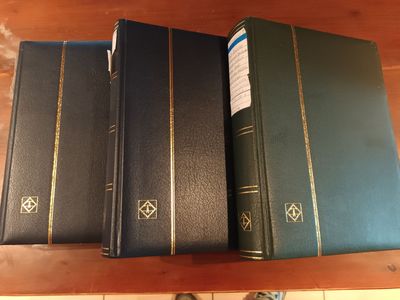 trois livres posés sur une table, à côté desquels se trouvent les pieds d'une personne