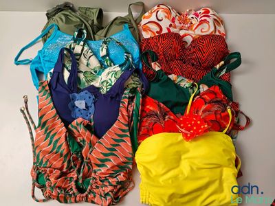 Plusieurs maillots de bain sont alignés sur une surface blanche