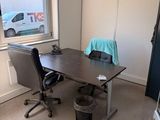 a desk with a chair and a trash can in the corner