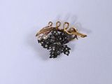 une broche en forme de fleur noire et dorée sur un fond blanc