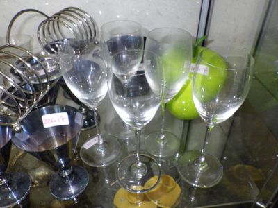 many wine glasses on a glass table with a green apple in the background