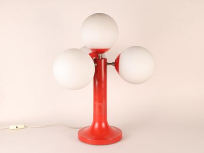 une lampe de table rouge sur laquelle sont posées trois boules blanches