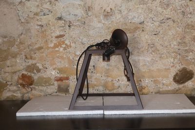un objet métallique posé sur une table, avec un mur de briques en arrière-plan