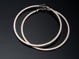 two silver hoop earrings on a black surface with a moon in the background