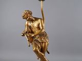une statue en or représentant un homme tenant une ampoule posée sur une table