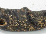 un objet en pierre percé d'un trou, posé sur une surface blanche