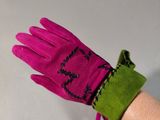 someone is holding a pair of pink gloves with a green wrist band