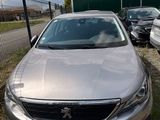 La voiture argentée est garée devant un parking clôturé.