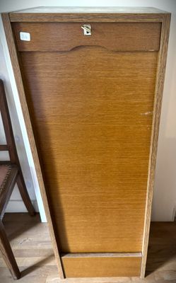 a wooden cabinet with a door and a chair next to it