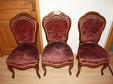 three red velvet chairs sitting next to each other on a wooden floor