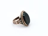 a close up of a ring with a black stone on it