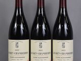 Trois bouteilles de vin sont alignées sur une table en verre