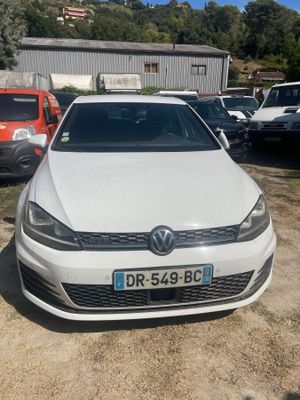 une Volkswagen Golf blanche garée sur un parking à côté d'autres voitures