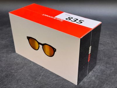 emballage d'une paire de lunettes de soleil posé sur une table, avec une boîte rouge et blanche