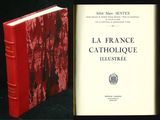 un livre ouvert posé sur une table, à côté d'un livre rouge